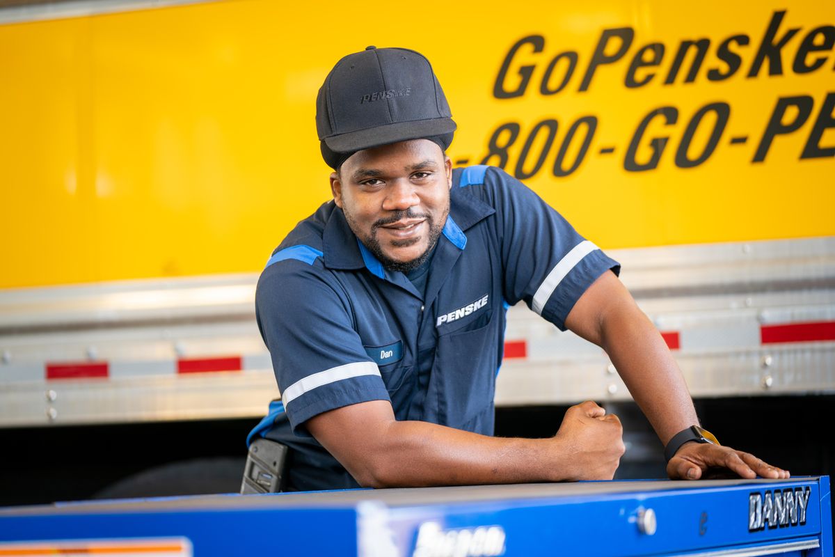 Penske technician posed in front of a Penske truck