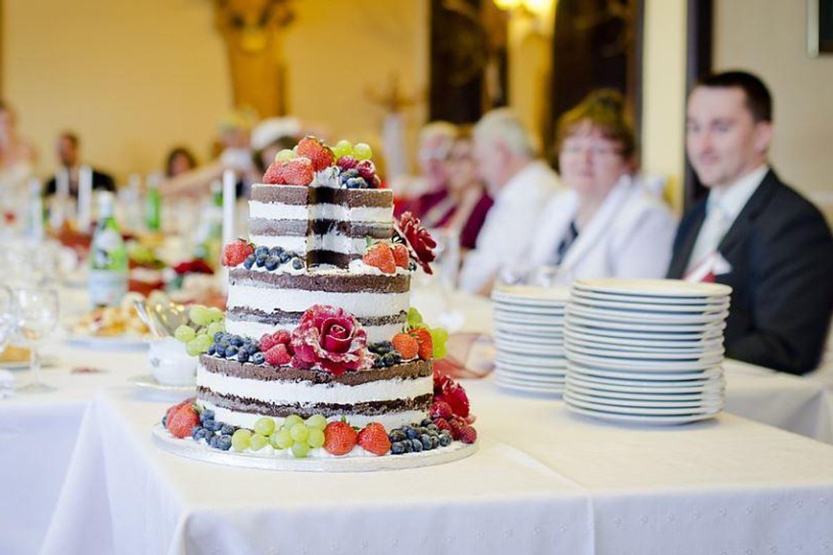 wedding cake surrounded by guests