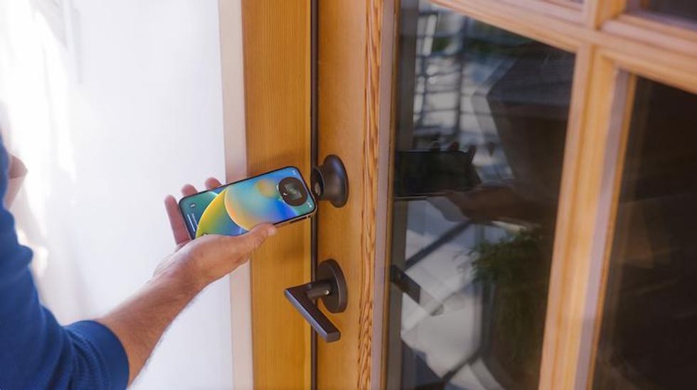 a photo of someone using Apple iPhone to unlock Level Lock+ smart lock on a door.