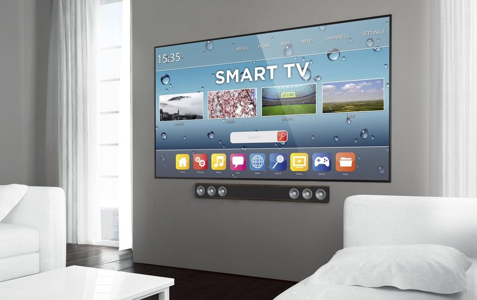 A photo of a large smart tv on a wall with a soundbar underneath