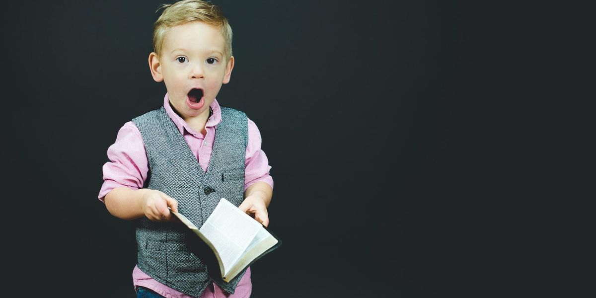 child with shocked expression holding leather bound journal