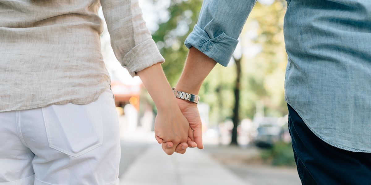 two people holding hands together on walkway during daytime