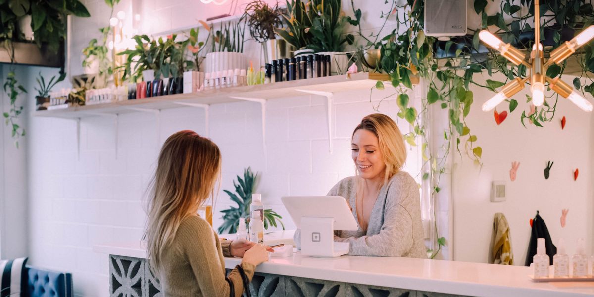 woman facing white counter making a purchase from female cashier