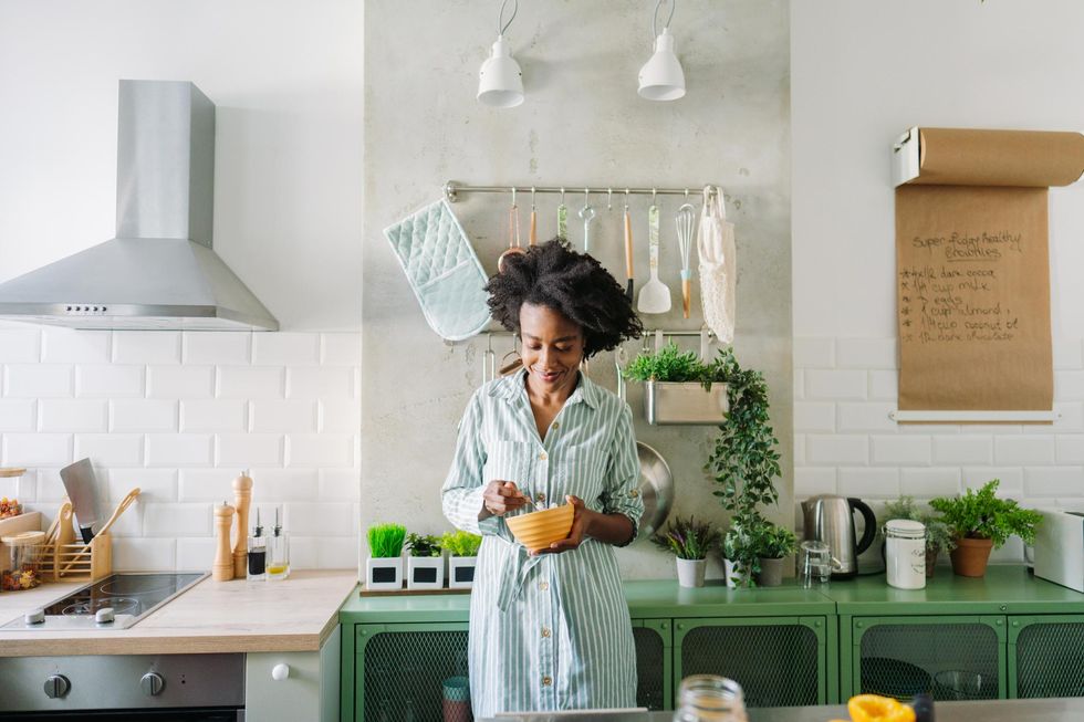 Black woman eating healthy food in kitchen