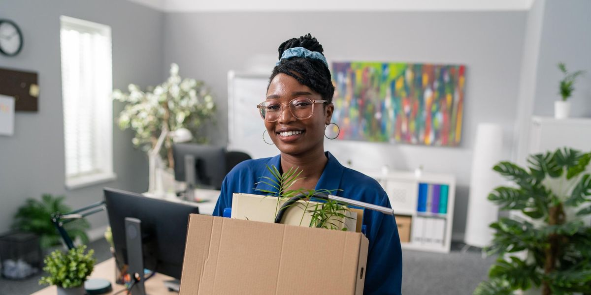 Black woman smiling with box of things from her office space