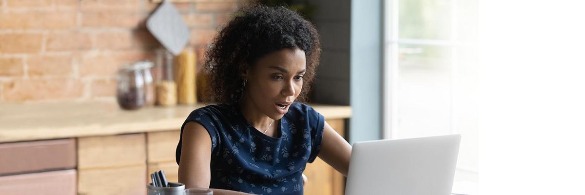 woman looking at her laptop in shock