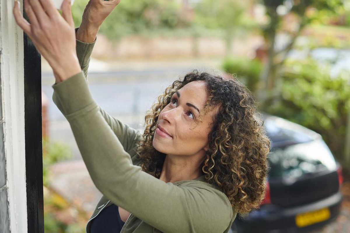 a woman installing an outdoor home security camera
