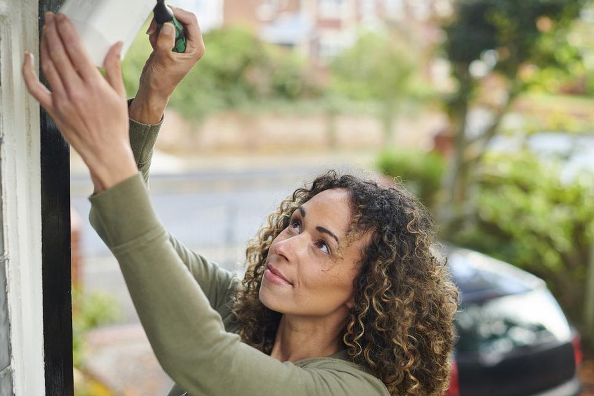 a woman installing an outdoor home security camera