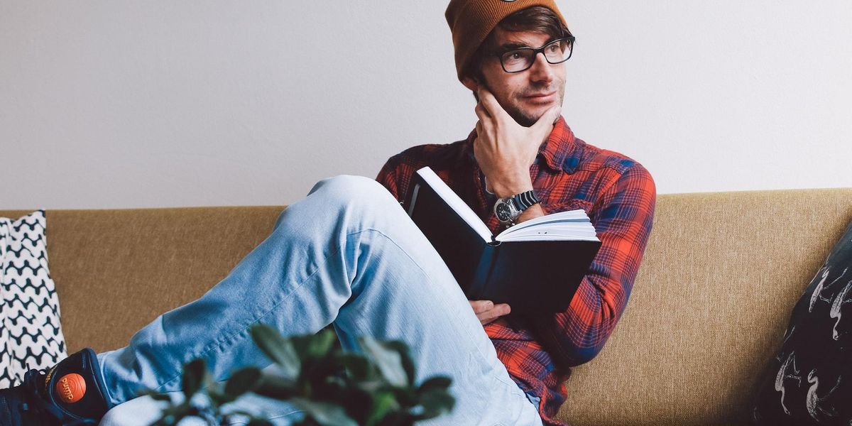 A young man sits and thinks while holding a book