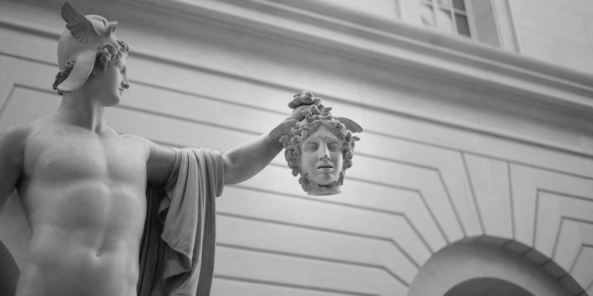 A Roman statue holds the head of another, in black and white