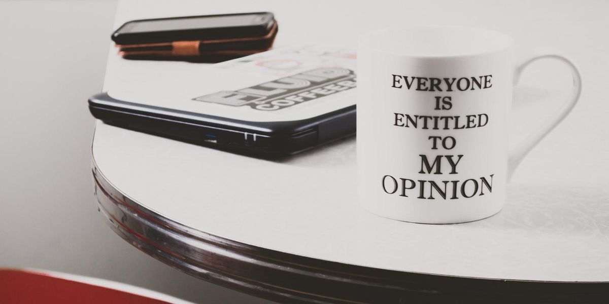 Photo of an iphone, laptop and mug that says "Everyone Is Entitled To My Opinion"