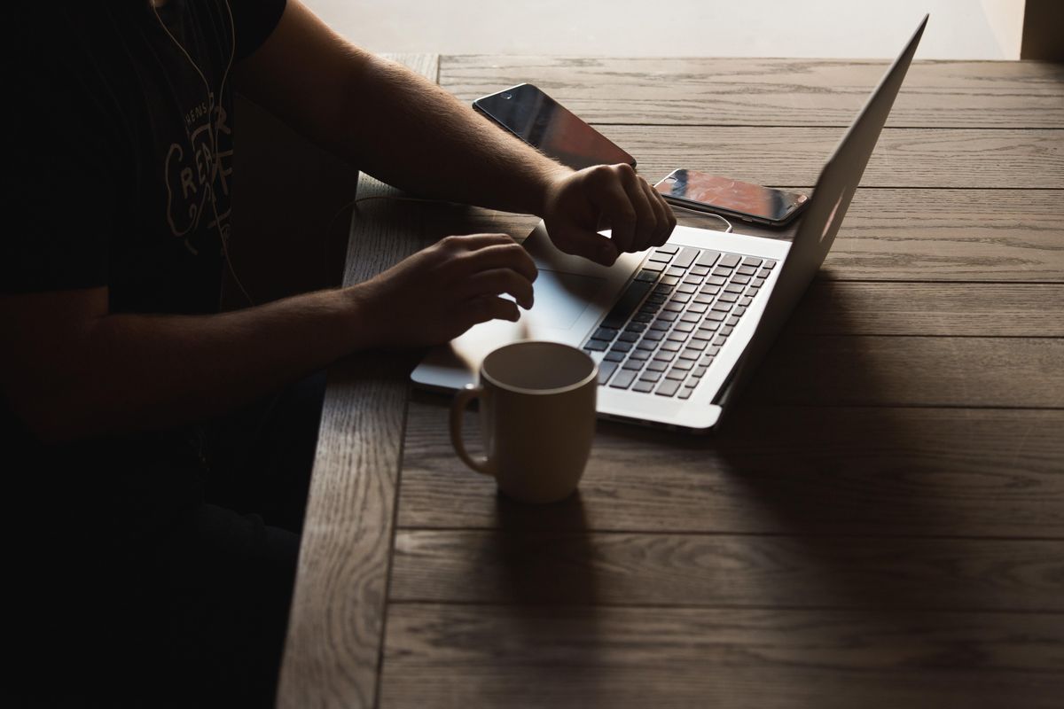 person typing at computer with a cup of coffee