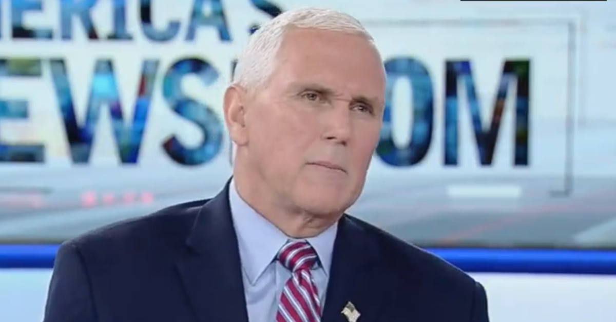 former Vice President Mike Pence, wearing a dark blue suit jacket, a light blue shirt, and a red, white, and blue striped tie