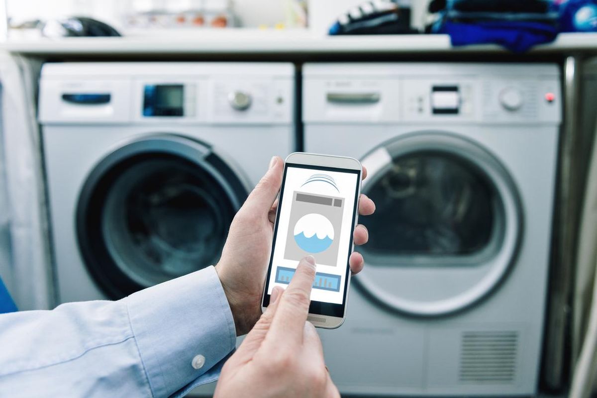 a photo of a smartphone with app controlling washing machine and dryer.