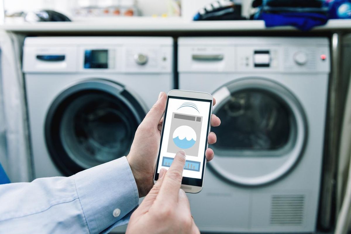 a photo of a smartphone with app controlling washing machine and dryer.