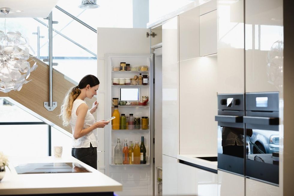 a photo of a woman using a smart refrigerator