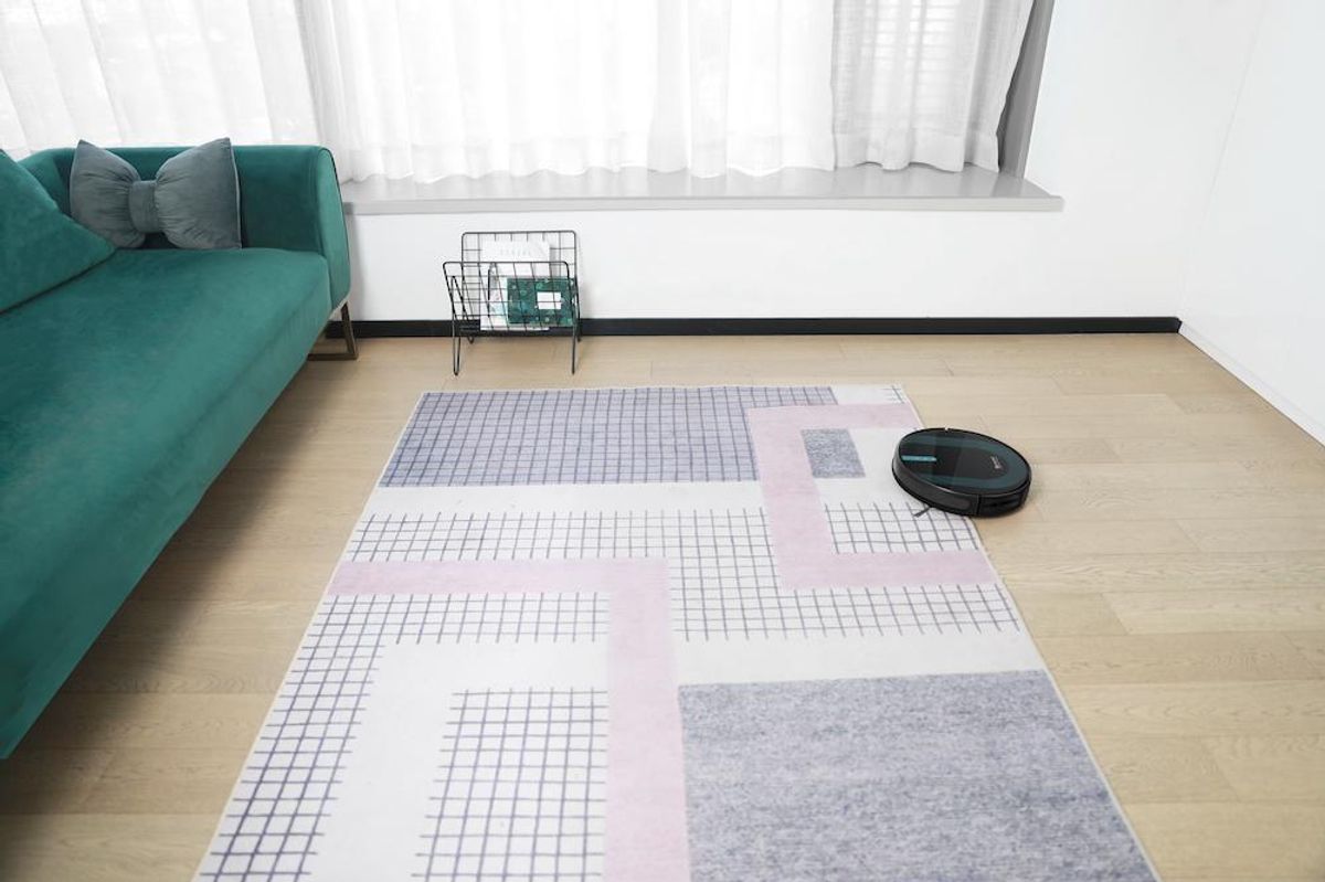 a photo of Proscenic 850T robot vacuum going up on a rug in a living room