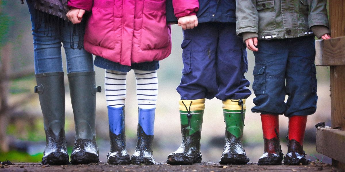 four children standing in muddy boots during daytime