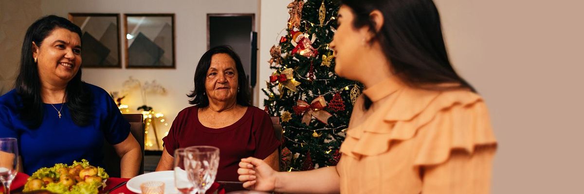 latino family grandma mom and daughter talking next to the christmas tree