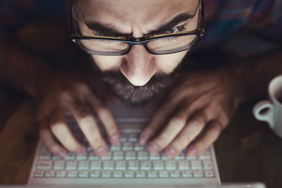 a photo of a man on a computer staring into a computer screen.