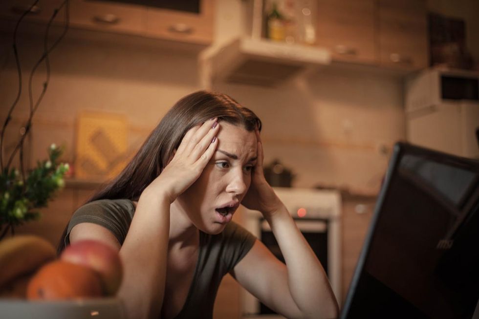 a photo of a woman in shock looking at her computer