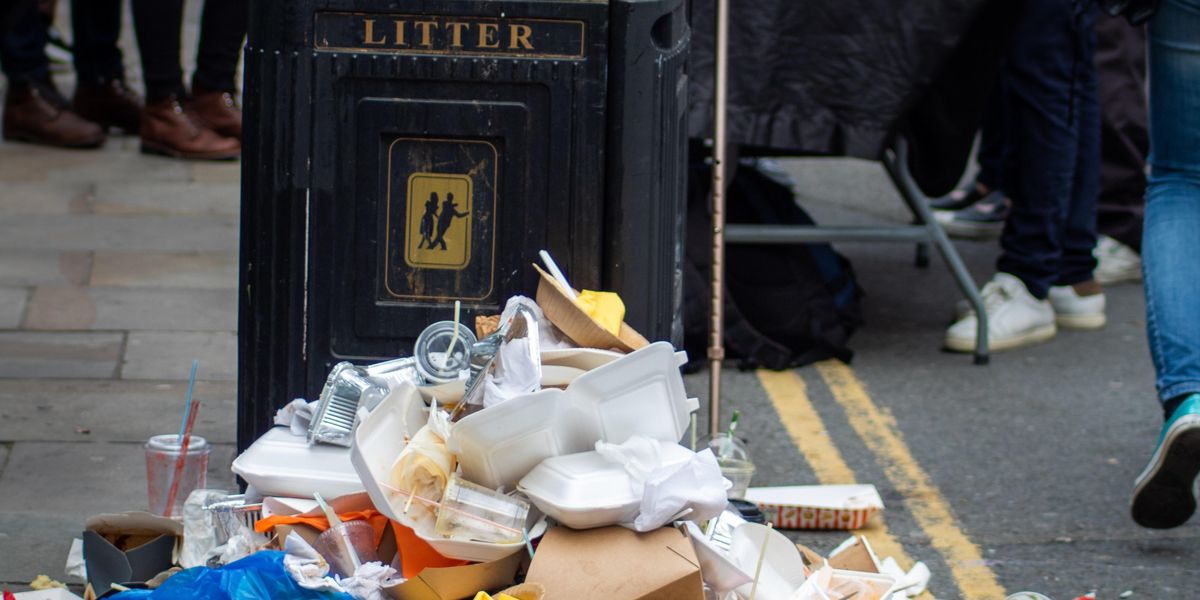 Trash pileup in front of public garbage bin