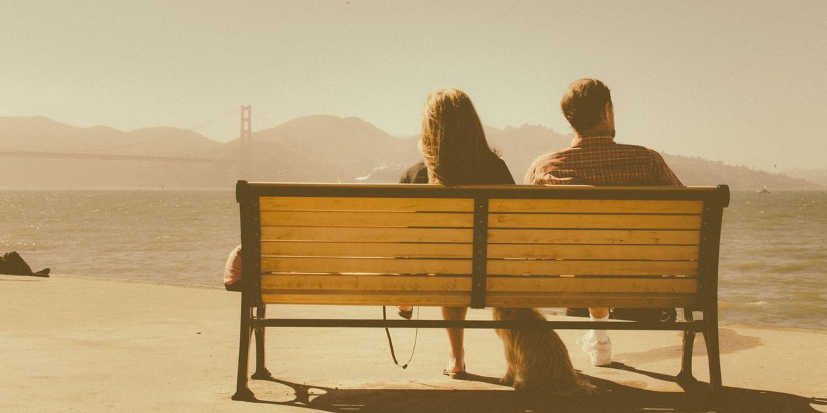 Back view of a couple sitting on a park bench and feeling distant