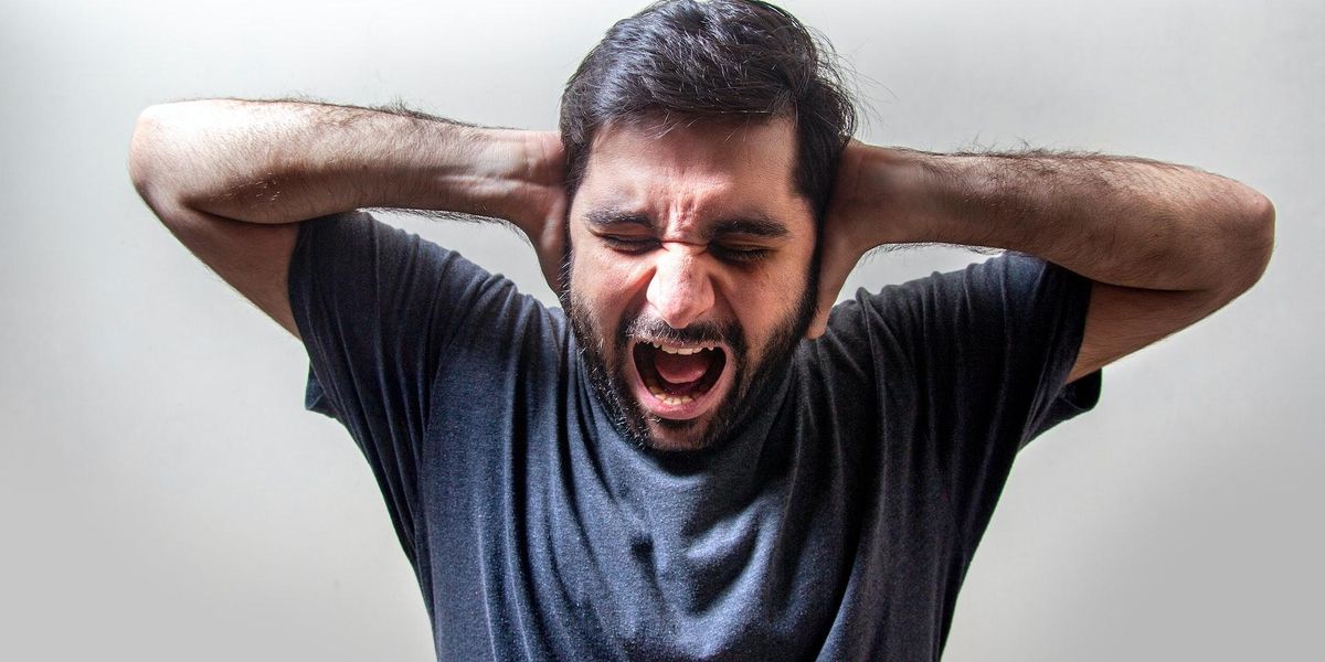 A man covers his ears and screams in frustration