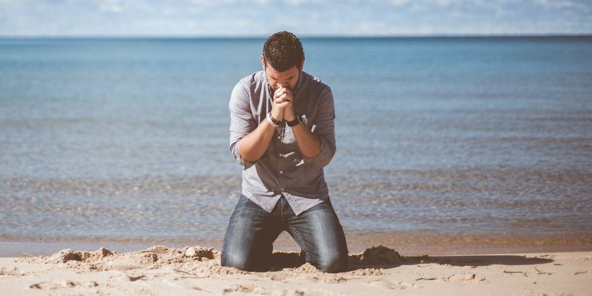 A man giving thankful prayers on a beach