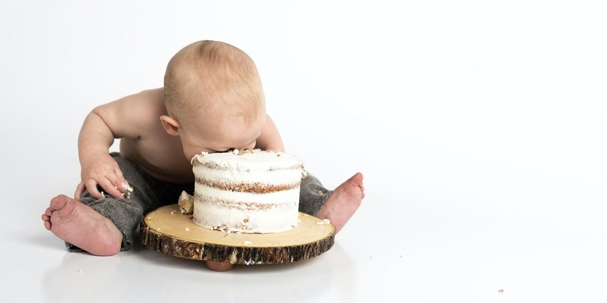 A baby has their face in a cake