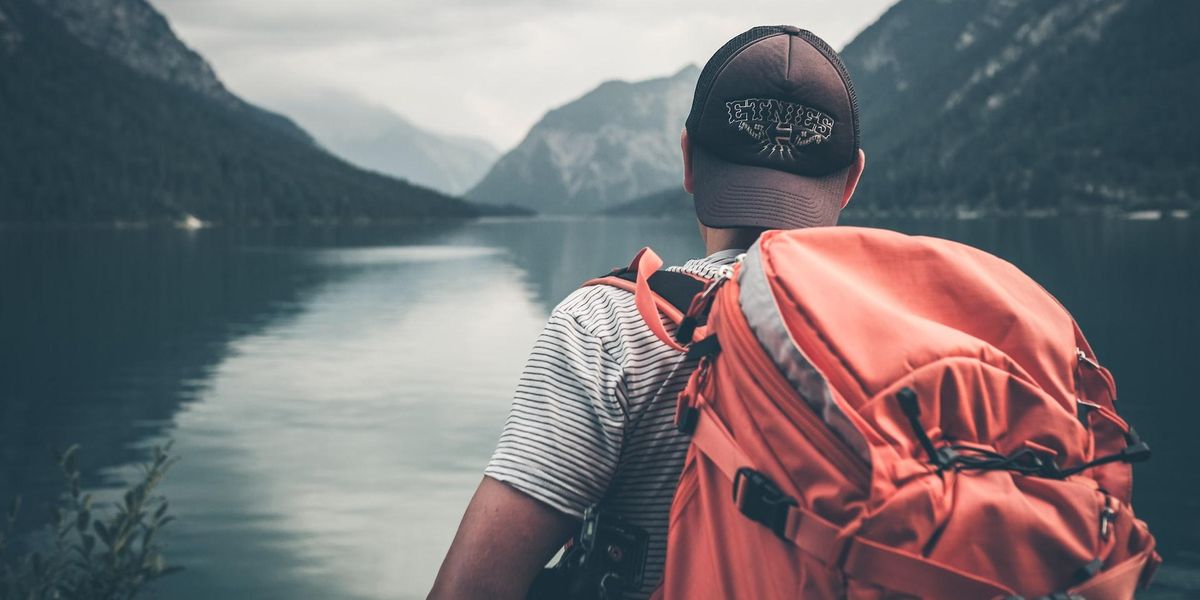 A man backpacking on river, heading towards mountains