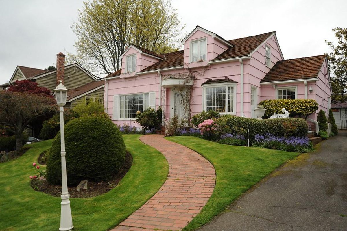 Pink house, with brick path, white lamp pole, yard, trees,…