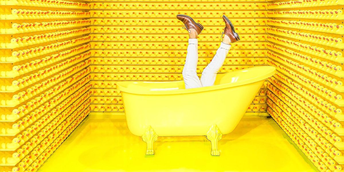 A yellow room. A yellow tub with legs pointing to sky, wearing white pants and brown shoes