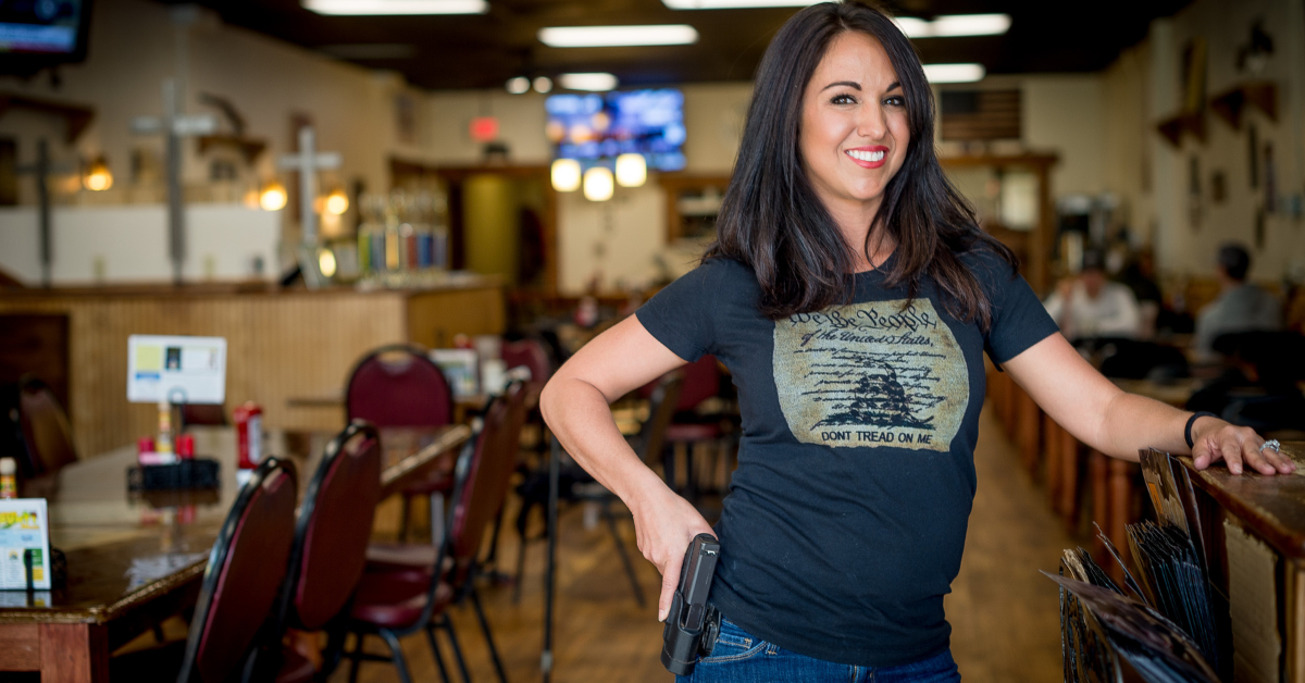 Lauren Boebert posing with her hand on her gun in her former restaurant, Shooters Grill