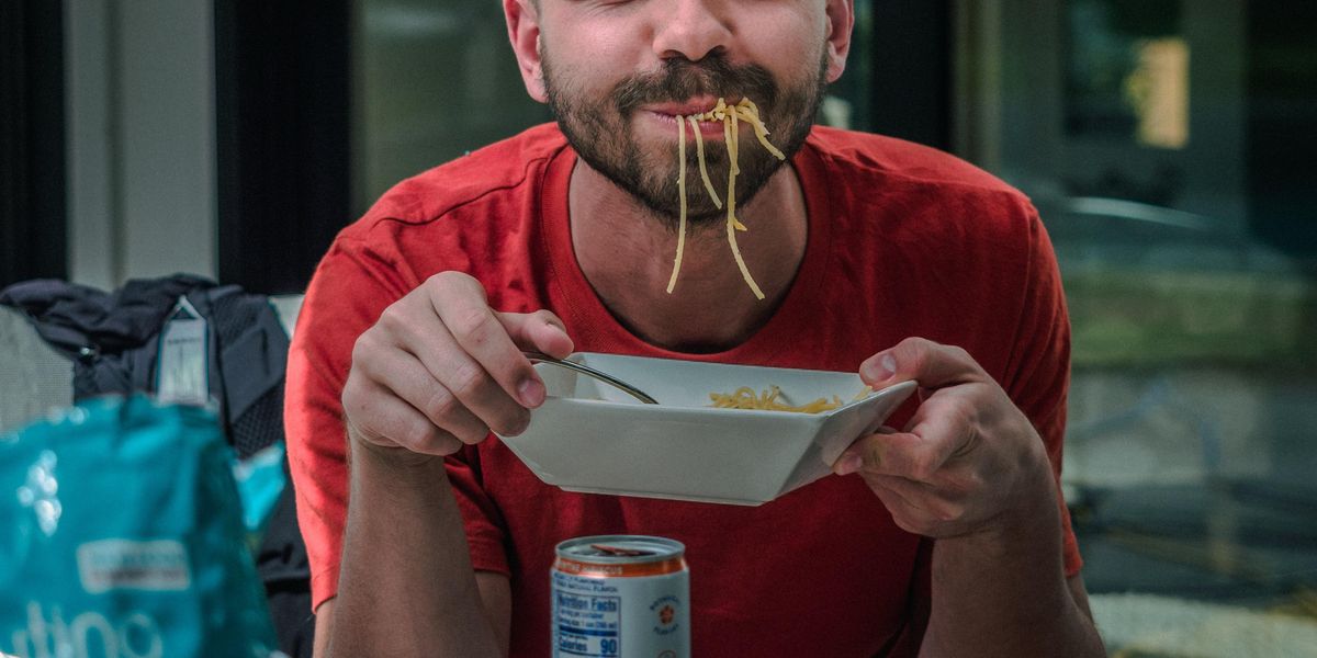 Man with noodles dangling from his mouth 