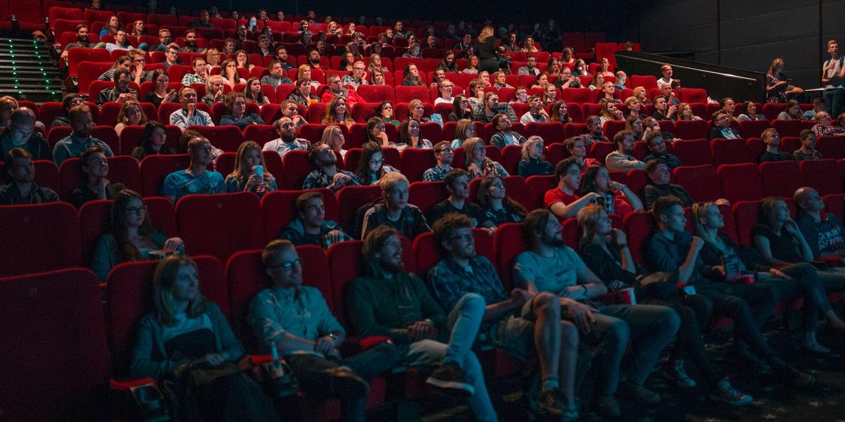 An audience sit in a theater watching a movie