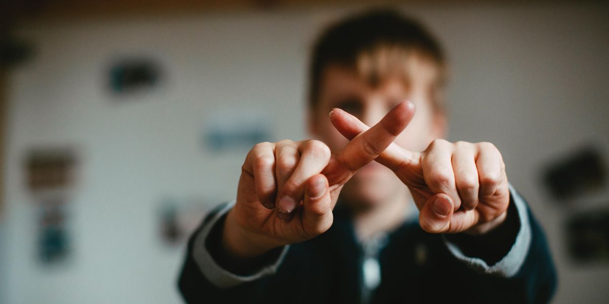 Kid forming a cross with two fingers
