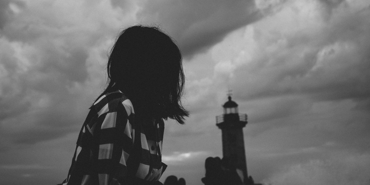 black and white photograph of a woman staring at a lighthouse