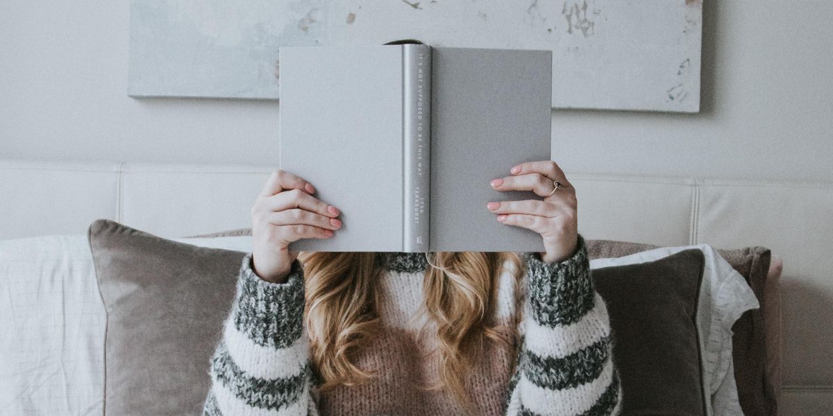 Woman holding book up in front of her face to read