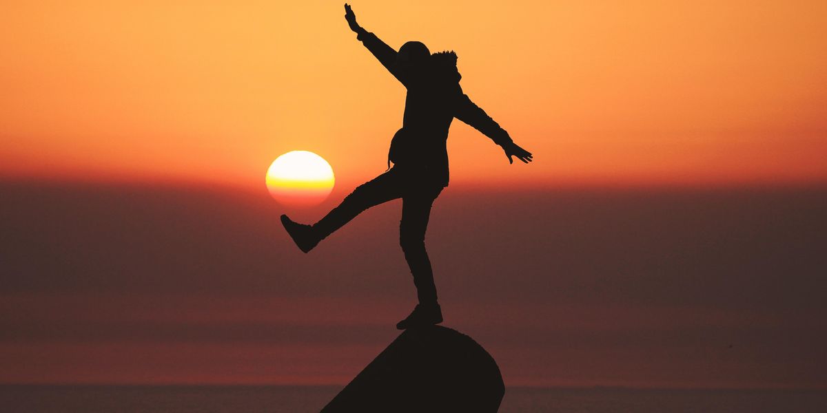 photo of silhouette photo of man standing on rock