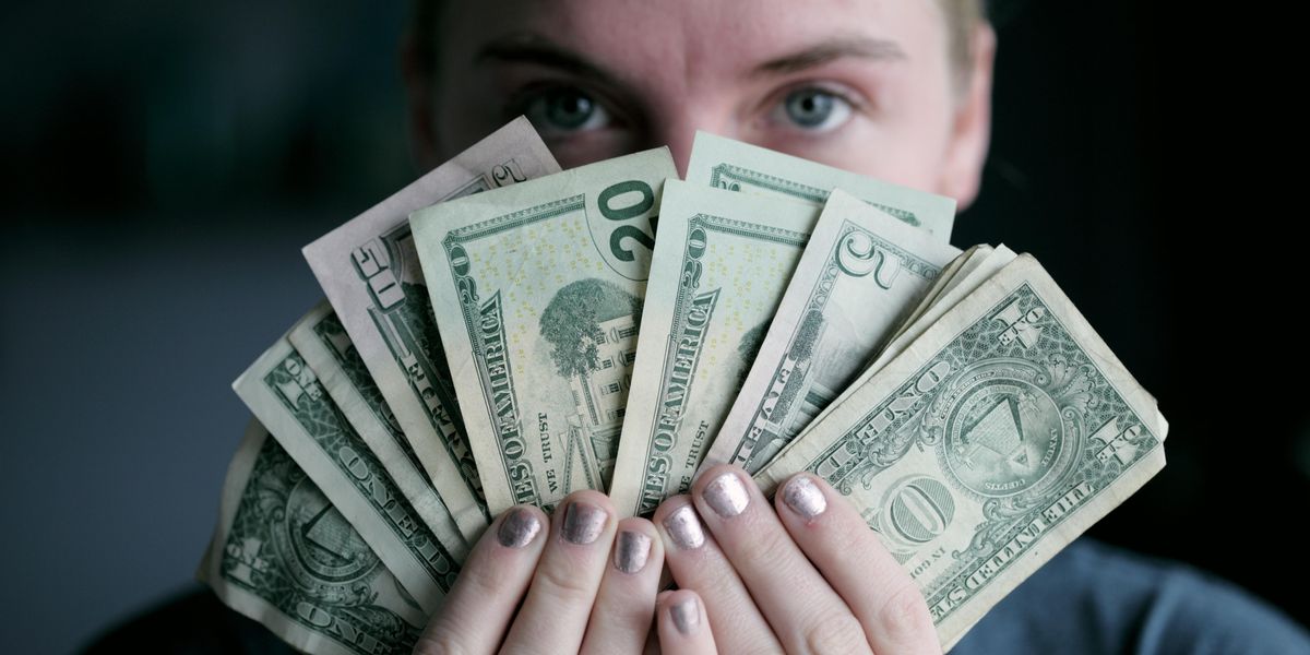 A person holding U.S. dollars in front of their face