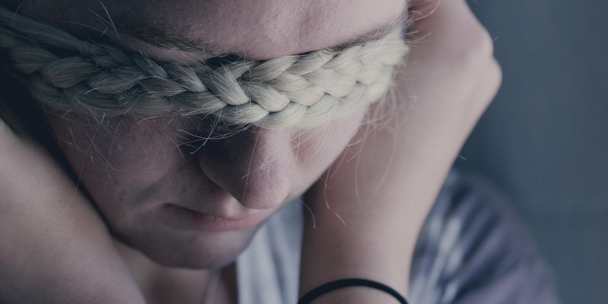 Woman covering eyes with braid