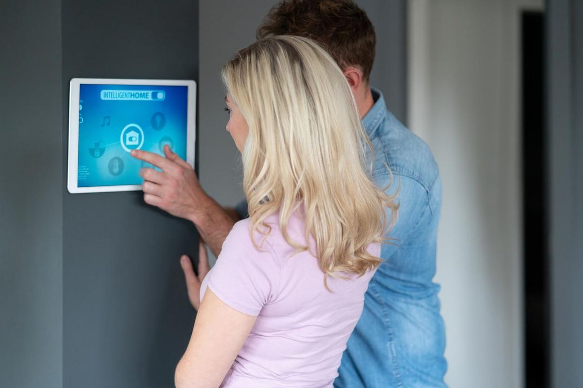 a photo of a couple using a tablet to set your their smart home security system