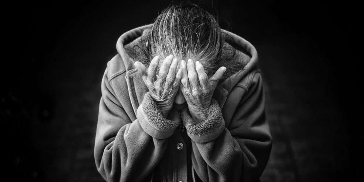 A woman holds her head in her hands, seemingly in despair