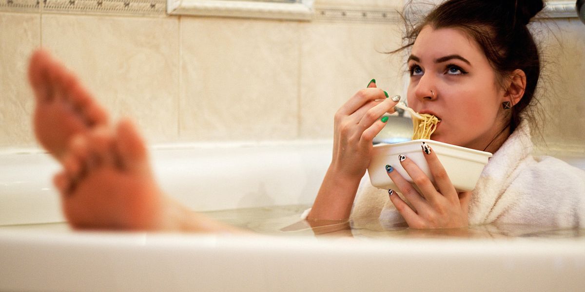 girl in bathtub holding white ceramic mug