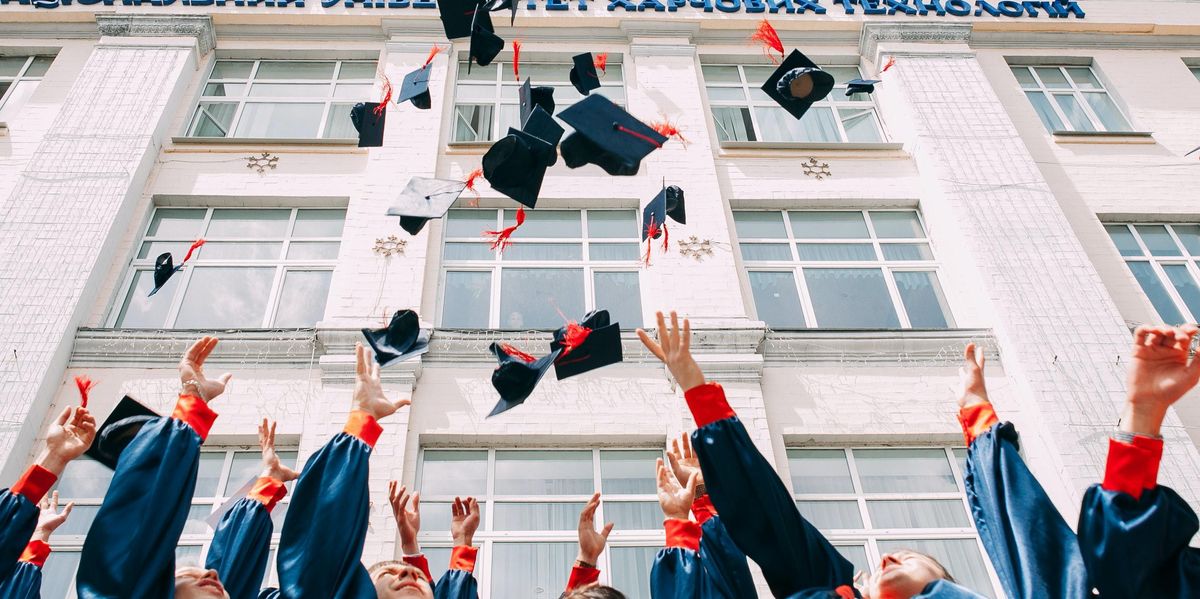 group of fresh graduates students throwing their academic hat in the air