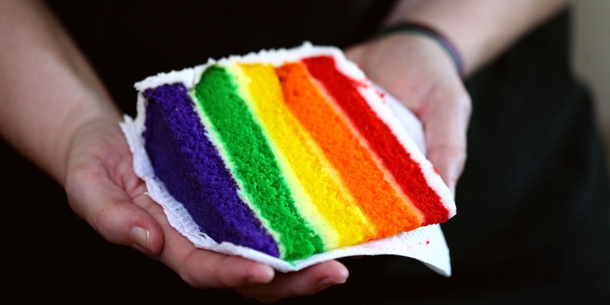 Person offering a slice of Pride cake