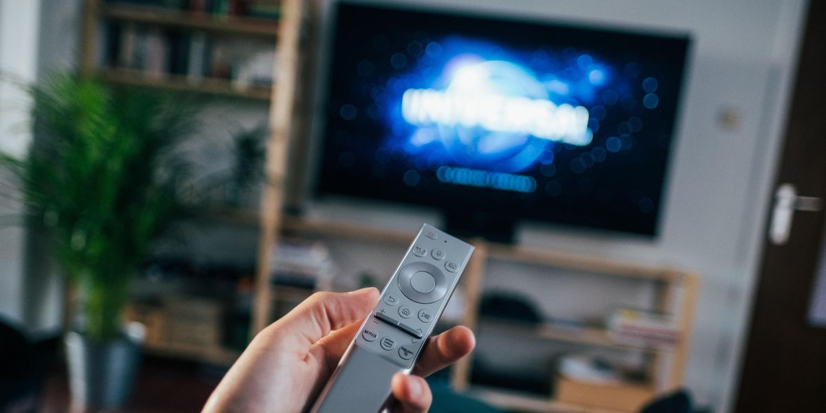 Person pointing remote at TV