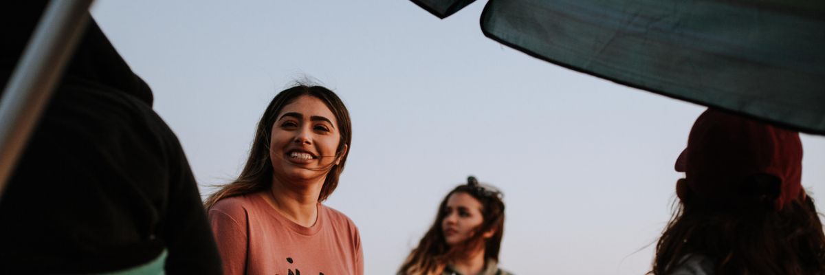 smiling woman wearing a tshirt sits cross-legged with three female friends 