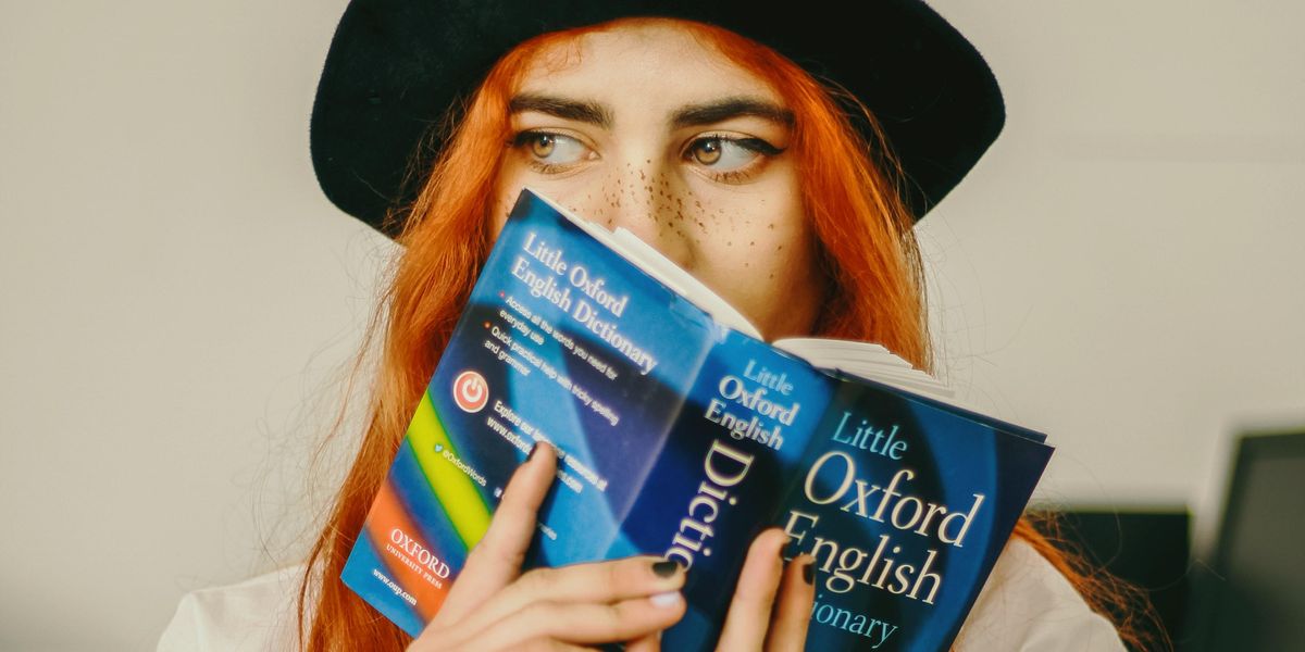 Woman holding up an Oxford English Dictionary